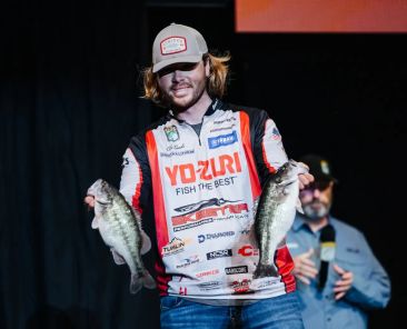 Cole Sands on stage with two bass at the 2024 Bassmaster Classic.