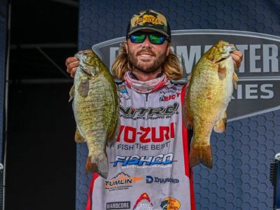 Cole Sands holding up two smallmouth bass on the Elite Series stage in 2023
